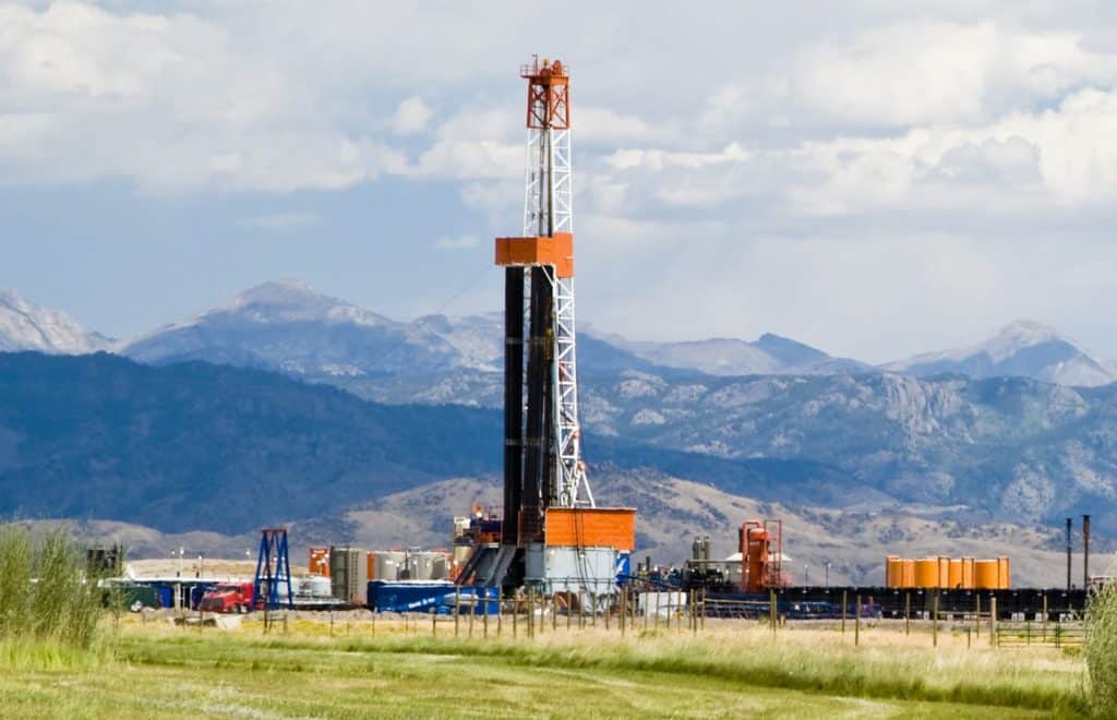 oil rig in field with mountains in background