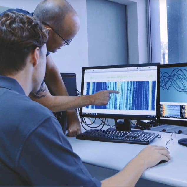 Engineer looking at Distributed Fiber Optic Sensing data on computer screens